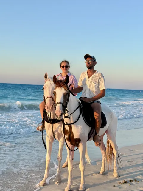 Julia and Nouh on horseback by the sea