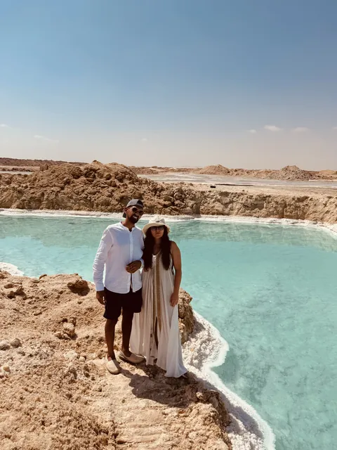 Julia and Nouh beside a turquoise pool in the desert